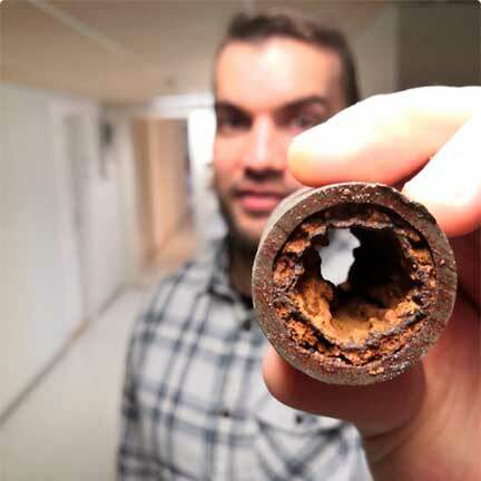 Kuvassa mies pitelee käyttövesiputken läpileikkausta.